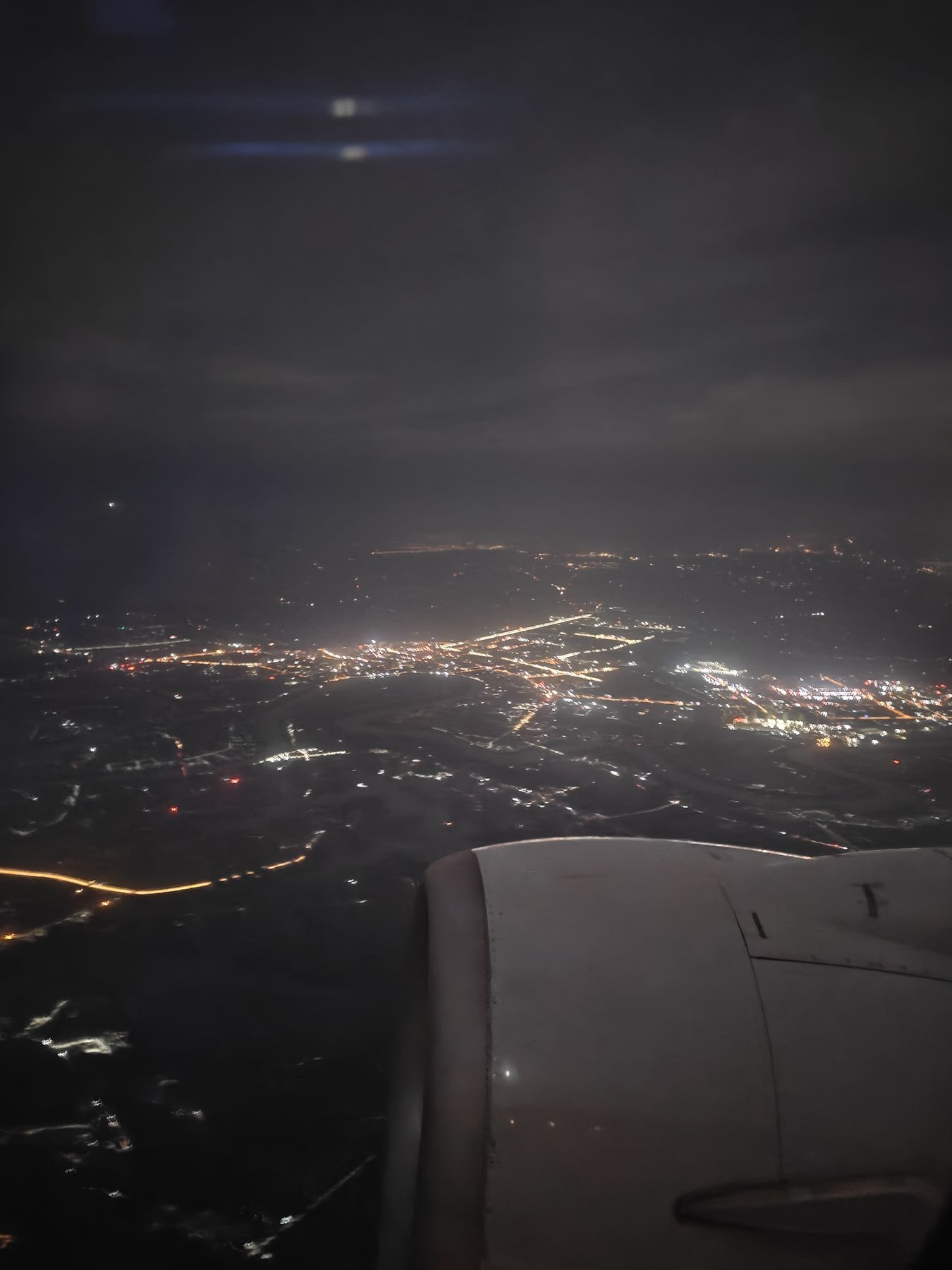 夜间航班舷窗外的城市灯光，橙色的道路灯网